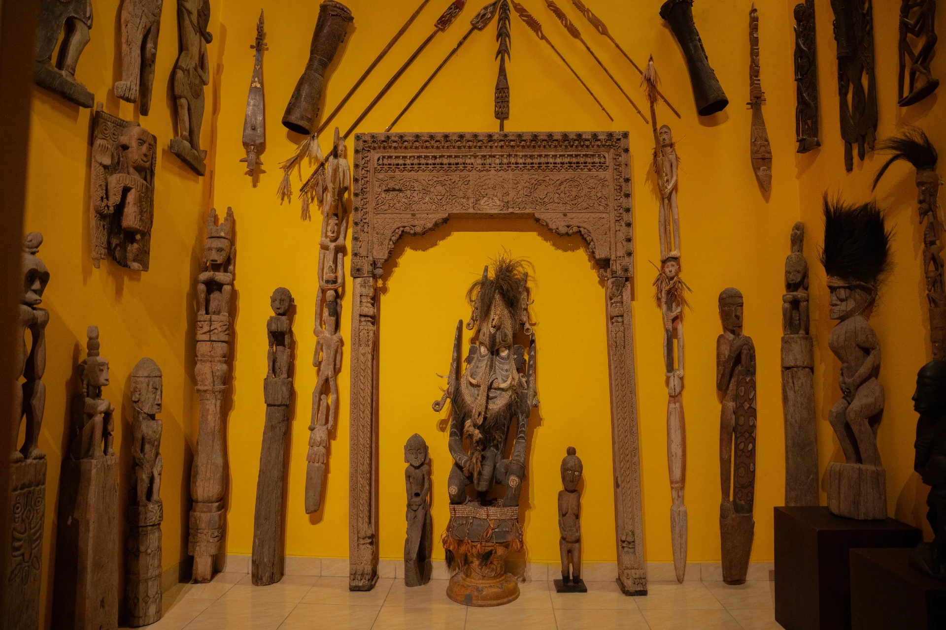 Curated display of ancient daggers, sharp staves, and masks representing historical combat and spirituality in the Scary Room.